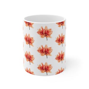 Könnte beinhalten: Weiße Keramiktasse mit einem sich wiederholenden Muster aus orangefarbenen und roten Dahlienblüten. Die Blumen haben mehrere Blütenblätter und sind vor einem weißen Hintergrund angeordnet. Die Tasse ist zylindrisch und für heiße oder kalte Getränke geeignet.
