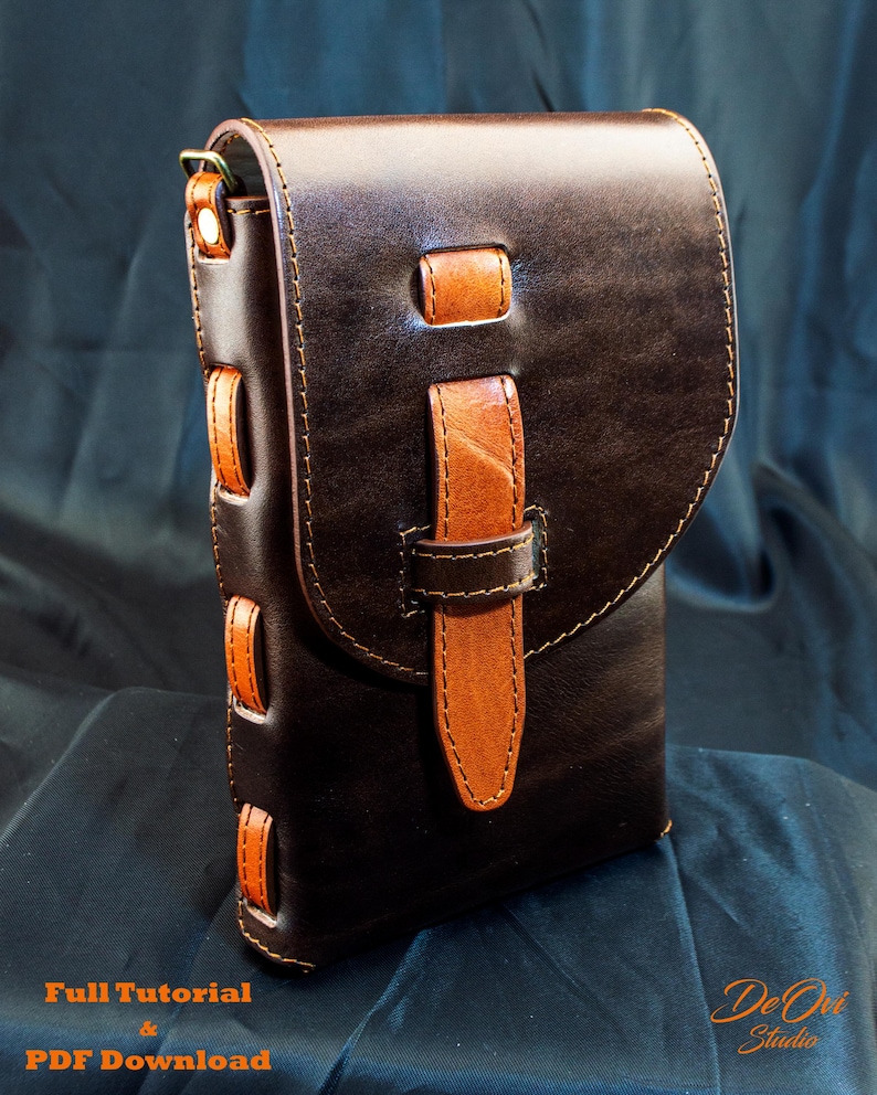 May include: A dark brown leather bag featuring a lighter tan leather strap closure and side accents. The bag has a flap top secured by a vertical strap. Text at the bottom reads Full Tutorial & PDF Download and De Ovi Studio.