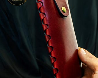 May include: A deep red leather glasses case featuring a scalloped edge design along the side, secured with a brass-colored metal snap button closure. The case has a smooth finish and a structured rectangular shape with rounded corners.
