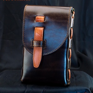 May include: A dark brown leather pouch featuring a lighter tan leather strap closure and side lacing details. The text "Full Tutorial & PDF Download" appears in the top left corner, and "De Ovi Studio" is printed in the bottom right corner.