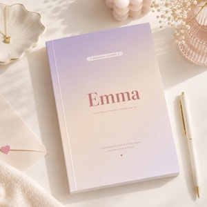 Könnte beinhalten: Ein Hardcover-Journal mit einem Verlauf von lila und pfirsichfarbenem Einband mit dem Titel "Emma". Das Journal enthält den Text "Personal Journal" und ein Zitat. Ein weißer Stift mit goldenen Akzenten liegt neben dem Journal.