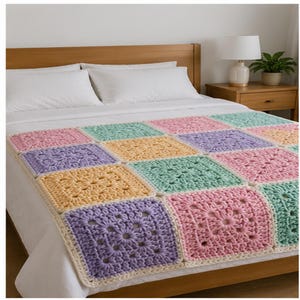 May include: A handmade crochet blanket featuring a repeating pattern of square motifs in pastel shades of light pink, mint green, lavender, and soft yellow, each bordered by a cream-colored yarn edge, laid flat across a white bedspread.
