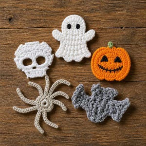 May include: A set of four crocheted Halloween decorations including a white ghost with black eyes, a white skull, an orange pumpkin with a black stitched face, and a grey bat. Below the skull is a beige crocheted spider with eight long legs.