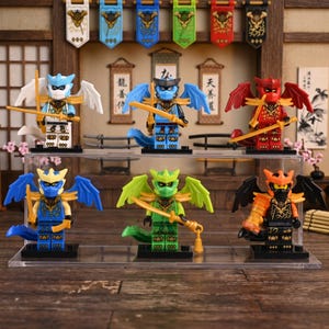 Puede incluir: Una colección de seis figuras de acción con temática de dragones, cada una con alas, espadas y esquemas de color únicos. Las figuras se exhiben en un estante transparente, con pancartas decorativas en el fondo.