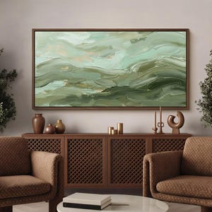 May include: Abstract landscape painting in shades of green and gold, framed in a dark wood. The artwork features textured brushstrokes, evoking a sense of movement. The painting hangs above a wooden cabinet with decorative items.