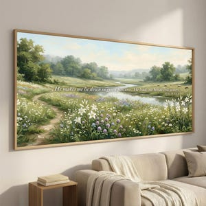 May include: A framed landscape painting depicts a serene meadow with a winding stream. The artwork features lush greenery, wildflowers, and a pathway. Text at the top reads, "He makes me lie down in green pastures. He leads me beside still waters. PSALM 23:2."