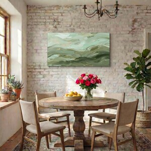 May include: A dining room scene featuring a round wooden table with four chairs. A vase of red and pink roses sits on the table. A landscape painting in shades of green hangs on the brick wall.