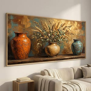 May include: A rectangular wall art print featuring three ceramic vases on a wooden surface. The left vase is orange with wavy lines, the center vase is gold with a crackled texture holding wheat stalks, and the right vase is a textured teal blue.