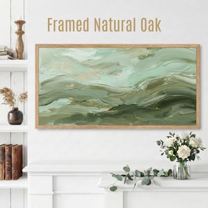 May include: Framed Natural Oak artwork. The rectangular artwork features an abstract painting in shades of green and beige, framed in natural oak. The painting has a textured, layered appearance, with visible brushstrokes. The artwork is displayed above a white mantel.