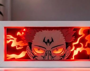 Könnte beinhalten: Eine weiße Leuchtbox mit einem detaillierten Bild eines Gesichts einer Figur und roten und orangen Flammen. Die Figur hat stachelige rote Haare, leuchtend orange Augen und ein schwarzes Tattoo auf der Stirn.