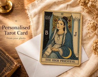 Può includere: Una carta dei tarocchi rettangolare con un'illustrazione della Papessa che mostra una luna crescente, un ciondolo a croce e un libro con l'etichetta TORA. La carta riporta il numero romano II, le lettere B e J e il testo THE HIGH PRIESTESS.
