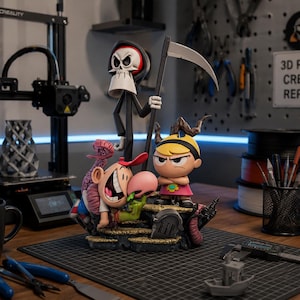 Peut inclure: Une figurine multi-personnages représentant un grand squelette en robe noire à capuche tenant une faux, un garçon souriant avec une pieuvre rose sur la tête et une fille blonde en robe rose, le tout sur un socle en pierre avec une pierre tombale RIP.