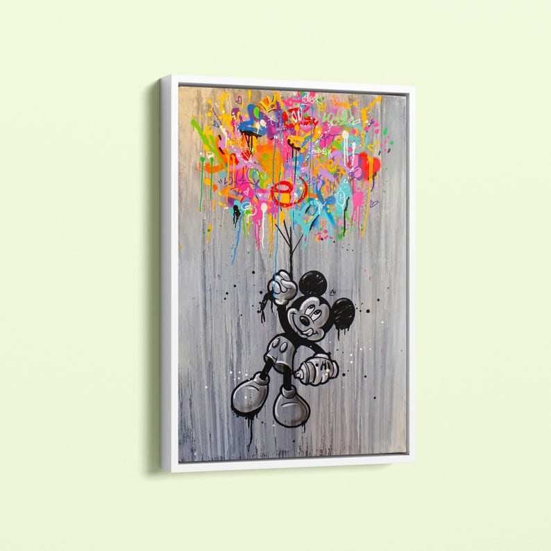 Peut inclure: Une &oelig;uvre encadr&eacute;e repr&eacute;sentant Mickey Mouse en noir et blanc, tenant un jet de peinture color&eacute;. Le fond est gris textur&eacute; avec des coulures et des &eacute;claboussures de peinture. L'&oelig;uvre est dans un cadre blanc.