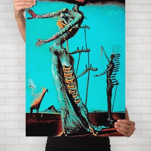 May include: An artistic print featuring surrealist figures against a turquoise background. The artwork depicts elongated forms, ladders, and a giraffe, with a palette of teal, brown, and red. The print is held up against a white brick wall.