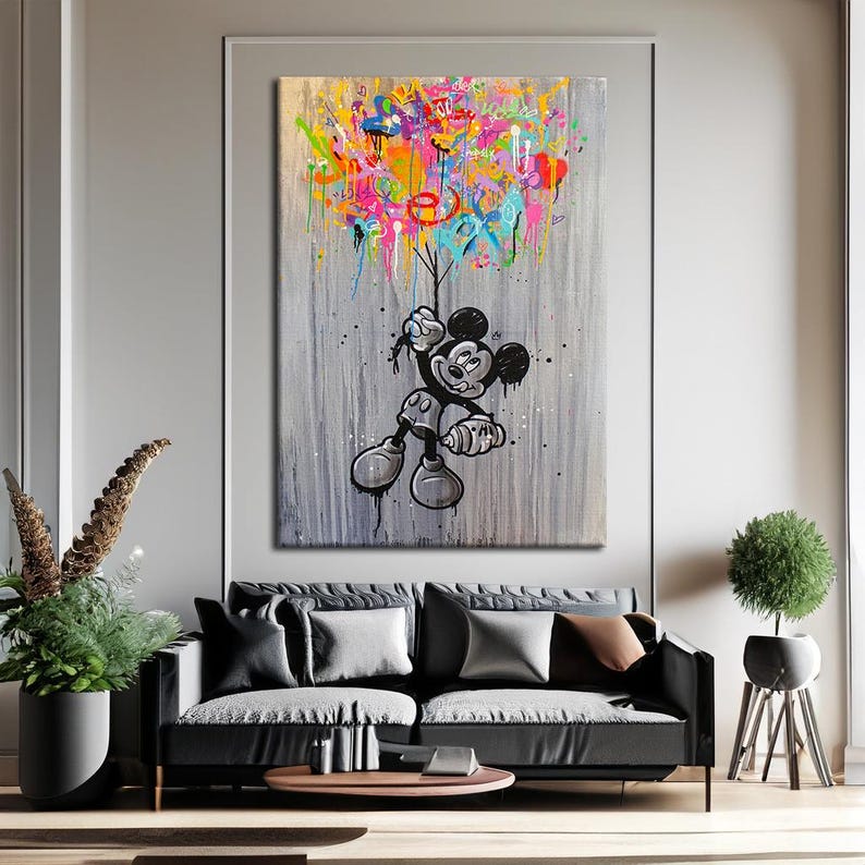 Peut inclure: Une grande toile d'art repr&eacute;sentant Mickey Mouse en noir et blanc, tenant des formes abstraites color&eacute;es. Le fond est gris textur&eacute;, avec des &eacute;claboussures de peinture ajoutant &agrave; l'ambiance vibrante de l'&oelig;uvre. L'&oelig;uvre est expos&eacute;e dans un salon moderne.