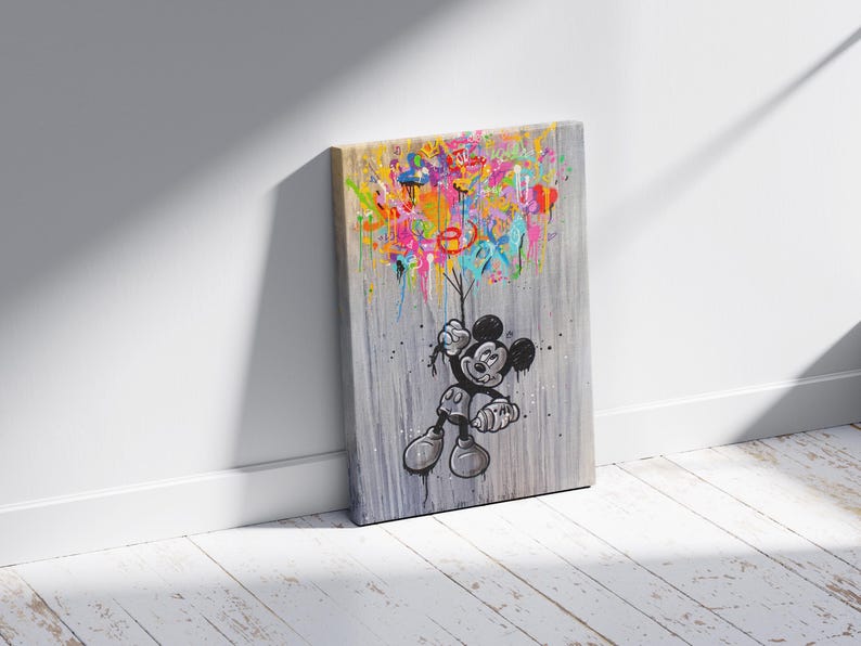 Peut inclure: Impression sur toile repr&eacute;sentant Mickey Mouse tenant des &eacute;claboussures de peinture color&eacute;es. L'&oelig;uvre d'art est en noir, blanc et gris avec des &eacute;claboussures vibrantes de rose, jaune, bleu et vert. Le mot "EX" est visible dans la peinture.