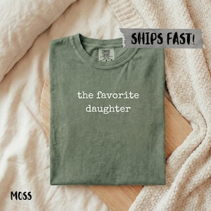 Moss green t-shirt with "the favorite daughter" text and "Ships Fast!" tag.
