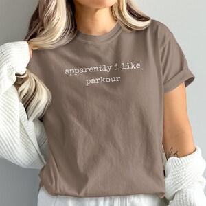 Brown t-shirt with "apparently i like parkour" text.