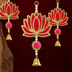 Può includere: Tre ornamenti decorativi sospesi con un design a fiore di loto. Ogni ornamento ha un centro rosso, un contorno dorato, accenti rosa, perle finte e una piccola campana dorata. Lo sfondo è rosso scuro.