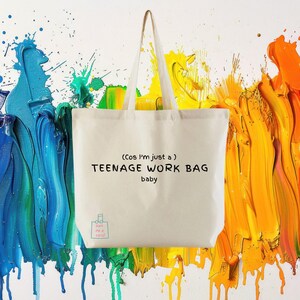 May include: A cream tote bag with the words "(Cos I'm just a) TEENAGE WORK BAG baby" printed in black. The bag has long handles and is set against a backdrop of blue, yellow, and orange paint splatters.