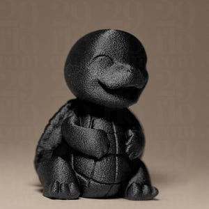 May include: A black, textured figurine of a smiling turtle-like creature. The figure has a rounded head, a shell-like back, and arms crossed over its chest. The figurine is sitting down.