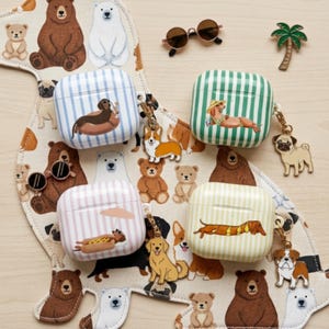 Puede incluir: Cuatro fundas cuadradas para AirPods con diseños de perros. Cada funda tiene un color y un patrón diferente, incluyendo rayas azules y blancas, verdes y blancas, rosas y blancas, y amarillas y blancas. Las fundas presentan ilustraciones de perros salchicha y otros perros.