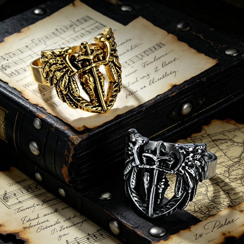 May include: Two rings with a shield and sword design. One ring is gold-colored, and the other is silver-colored. The rings are set against a backdrop of aged paper and a dark, textured surface, creating a vintage aesthetic.