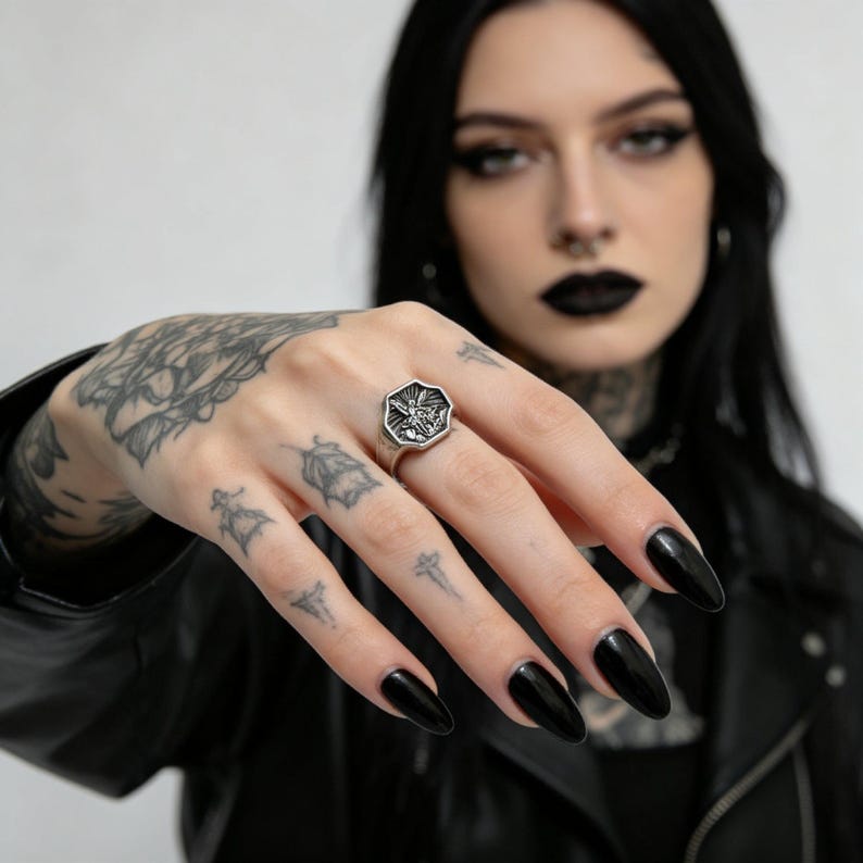 Peut inclure: Une bague argent&eacute;e avec une face octogonale orn&eacute;e d'un motif d&eacute;taill&eacute;. La bague est port&eacute;e au doigt, mettant en valeur ses d&eacute;tails complexes. Le motif de la bague semble &ecirc;tre un embl&egrave;me ou un symbole stylis&eacute;.