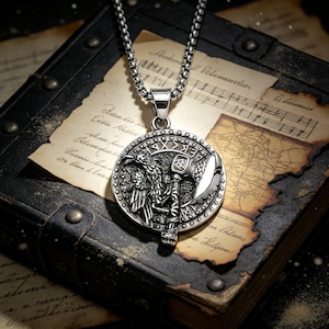 May include: Silver-toned pendant necklace featuring a detailed Viking design. The round pendant showcases a warrior figure, an axe, and runic symbols. The necklace has a chain with a square link design, and is set against a backdrop of aged paper and a leather-bound book.