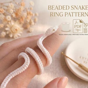 Pode incluir: Um padrão de anel de cobra com contas brancas, incluindo um ícone de download digital em PDF, um carretel de linha e uma tesoura. O texto diz BEADED SNAKE RING PATTERN e DIGITAL DOWNLOAD | PRINTABLE INSTRUCTIONS.