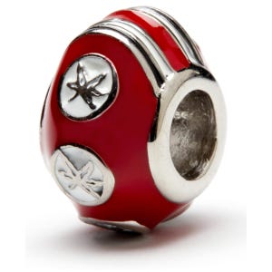 May include: Red and white charm bead with a silver metal ring. The bead has a red enamel base with two white circles featuring a stylized leaf design.