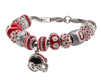 May include: A silver charm bracelet with red and white beads, a football charm, and a charm of a football helmet. The beads are decorated with rhinestones.