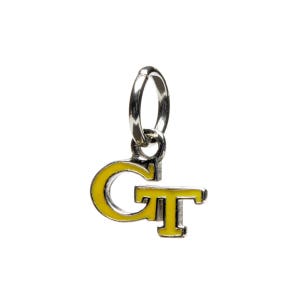 May include: A silver charm with a yellow 'GT' logo. The charm has a ring for attaching to a bracelet or necklace.