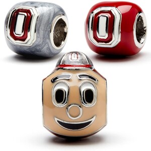 May include: Three charm beads featuring the Ohio State Buckeyes logo. One bead is red, one is silver, and one is a cartoon of Brutus Buckeye, the mascot, with a red cap.