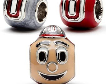 May include: Three charm beads featuring the Ohio State Buckeyes logo. One bead is red, one is silver, and one is a cartoon of Brutus Buckeye, the mascot, with a red cap.