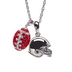 May include: Silver-toned necklace with two pendants: a football and a football helmet. The football pendant is covered in red and white crystals. The helmet pendant is silver with a black interior.