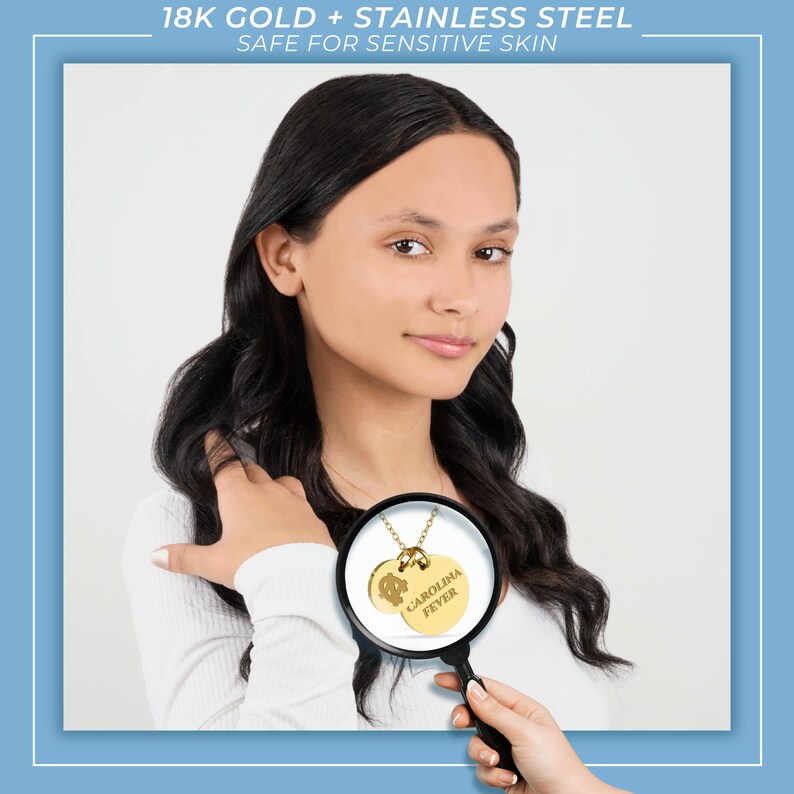 May include: A close-up of a gold necklace with two round pendants. The larger pendant says "CAROLINA FEVER" and the smaller pendant has a design. The necklace is being held by a magnifying glass.