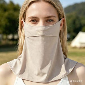 May include: A beige sun protection face cover with a neck drape. The face cover is made of a lightweight fabric and covers the nose, mouth, and neck. The person is wearing a white tank top.