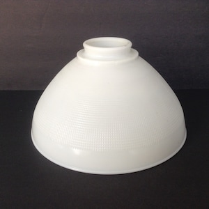 May include: A white, dome-shaped lampshade with a textured, grid-like pattern. The lampshade has a rounded base and a cylindrical top. The shade is made of opaque glass or ceramic and is designed to diffuse light.