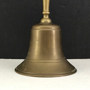 May include: A brass bell with a rounded base and a smooth, polished finish. The bell has a simple, elegant design.