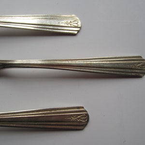 May include: Three silver-plated spoons with ornate handles. The handles have a decorative design with a floral motif and two hearts.