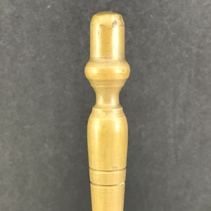 May include: A close-up of a wooden dowel with a rounded top. The dowel is light brown and has a smooth, polished finish.