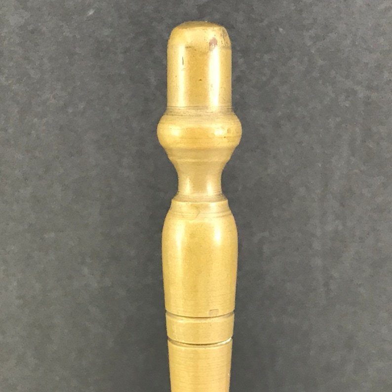 May include: A close-up of a wooden dowel with a rounded top. The dowel is light brown and has a smooth, polished finish.