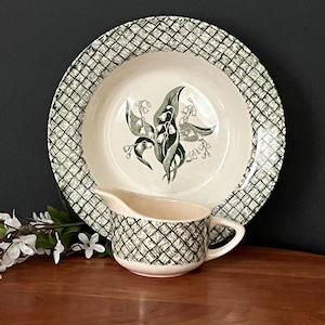 May include: A vintage green and white soup bowl and gravy boat with a lily of the valley design. The bowl and gravy boat have a woven pattern.