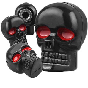 May include: Several black skull-shaped items with red eye sockets. The skulls have detailed features and a glossy finish. The objects are likely decorative or functional, possibly car accessories.