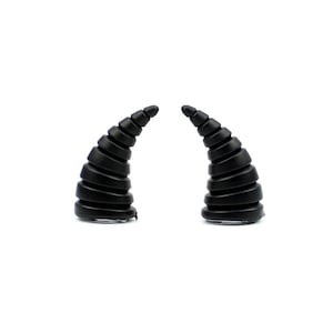 May include: A pair of black, curved horns with a spiral design. The horns are made of a solid material and are set against a white background. These are likely costume accessories.