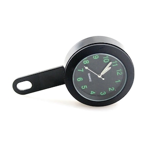 Puede incluir: Un reloj de cuarzo negro con esfera redonda y soporte de montaje negro. La esfera tiene números y manecillas verdes, y la palabra "QUARTZ" está impresa debajo. Diseñado para motocicletas o vehículos.