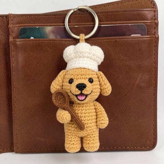 A hand-crocheted golden retriever dressed as a tiny chef — the kind of miniature amigurumi detail work that makes you stop scrolling.