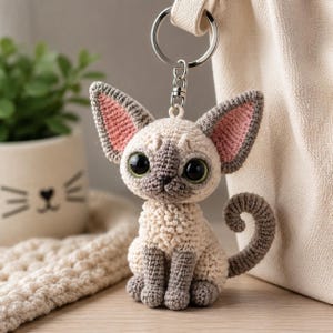 Portachiavi amigurumi a forma di gatto Devon Rex, realizzato a mano all'uncinetto, con ciondolo a forma di gattino dal pelo riccio.