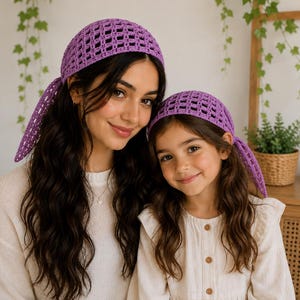 May include: Two matching purple crochet headscarves featuring an open-work grid pattern. Each headscarf is tied at the back with two long, dangling ends. The crochet design consists of a repeating square lattice structure in a vibrant violet hue.